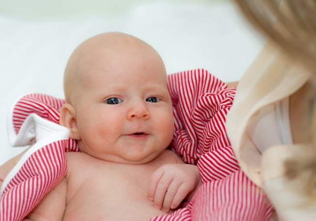 Ein wunderschönes Baby in einer roten Decke im Arm der Mutter - Fotoshooting Newborn Erlangen