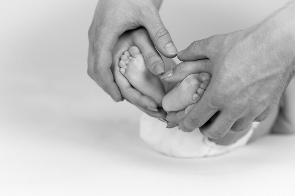 Die Hände der Eltern und die Füße des Neugeborenen bilden ein Herz