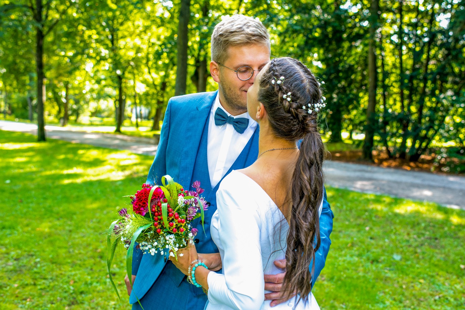 Hochzeitsfotograf Erlangen-Hochzeitspaar küsst sich liebevoll bei strahlendem Sonnenschein draußen im Park auf einer grünen Wiese