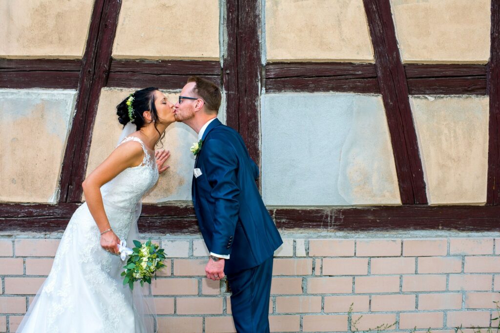 Brautpaar küsst sich vor Fachwerkhaus - Familien- und Hochzeitsfotograf Erlangen