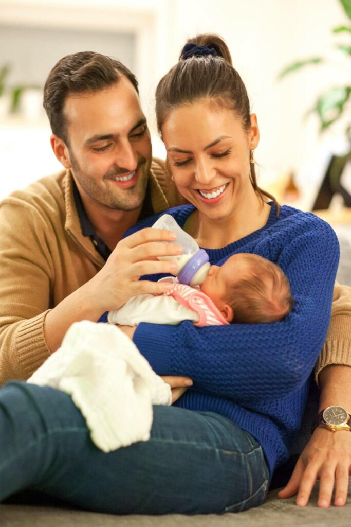 Mann gibt Baby die Flasche, Frau hält dabei das Baby im Arm - Familienfotos Erlangen