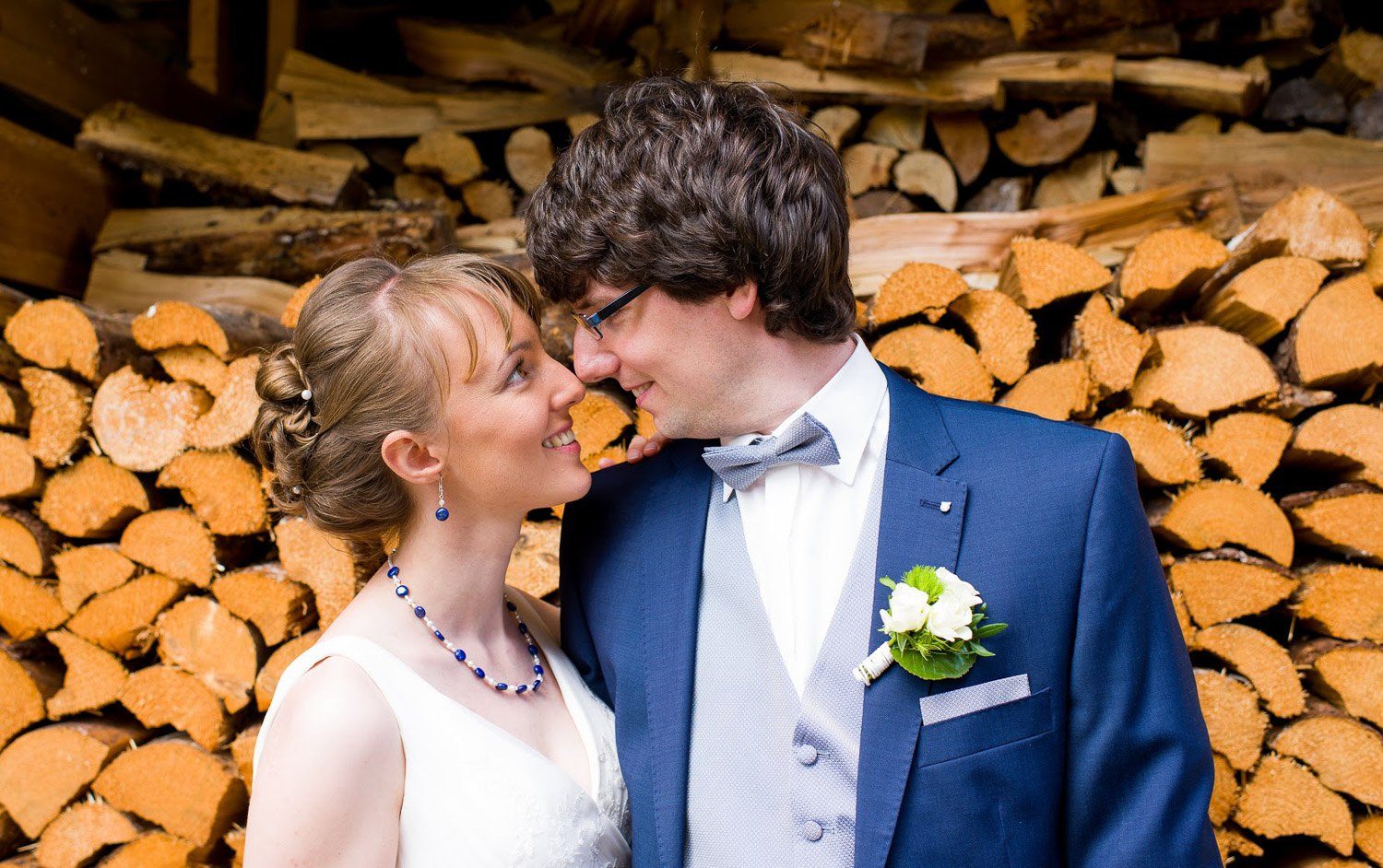 Hochzeitsfotograf Erlangen-Ein Brautpaar sieht sich innig in die Augen. Dahinter ist ein geschlichteter Stapel Holz zu sehen,